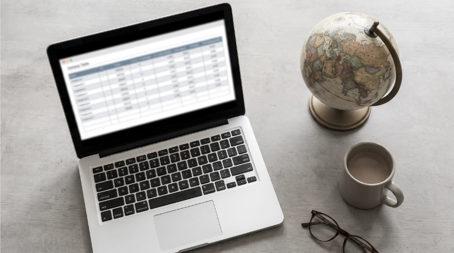 Laptop displaying a comparison table next to a world globe, representing country-by-country legal guidance
