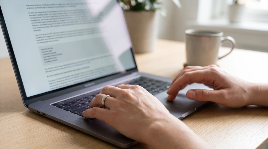Hands scrolling through a Terms of Service document open on a laptop
